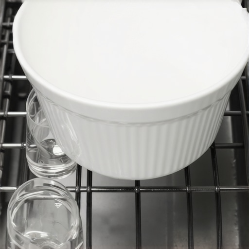 A bowl of vinegar placed in a dishwasher to remove hard water mineral buildup.